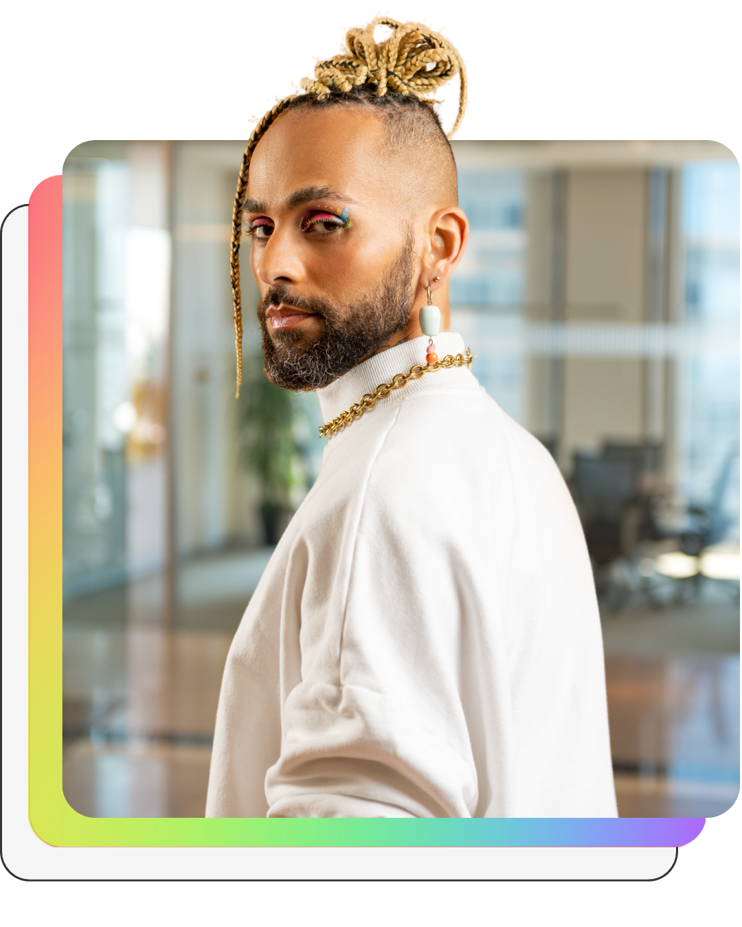 Homem negro de tranças olhando para a câmera com maquiagem colorida nos olhos. Ele usa camisa branca e cordões dourados.