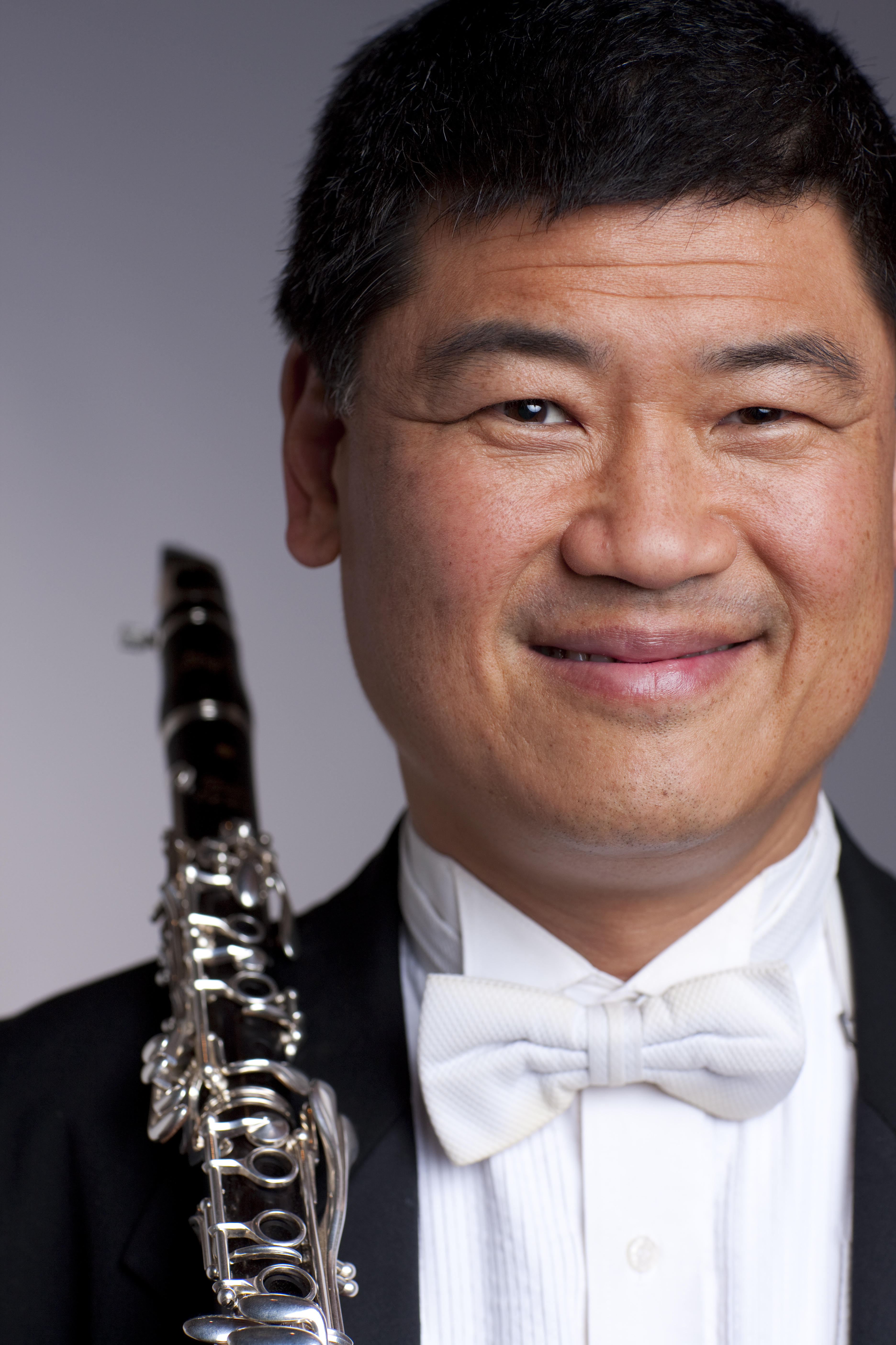 close up of a smilling John Yeh holding his clarinet over his right shoulder