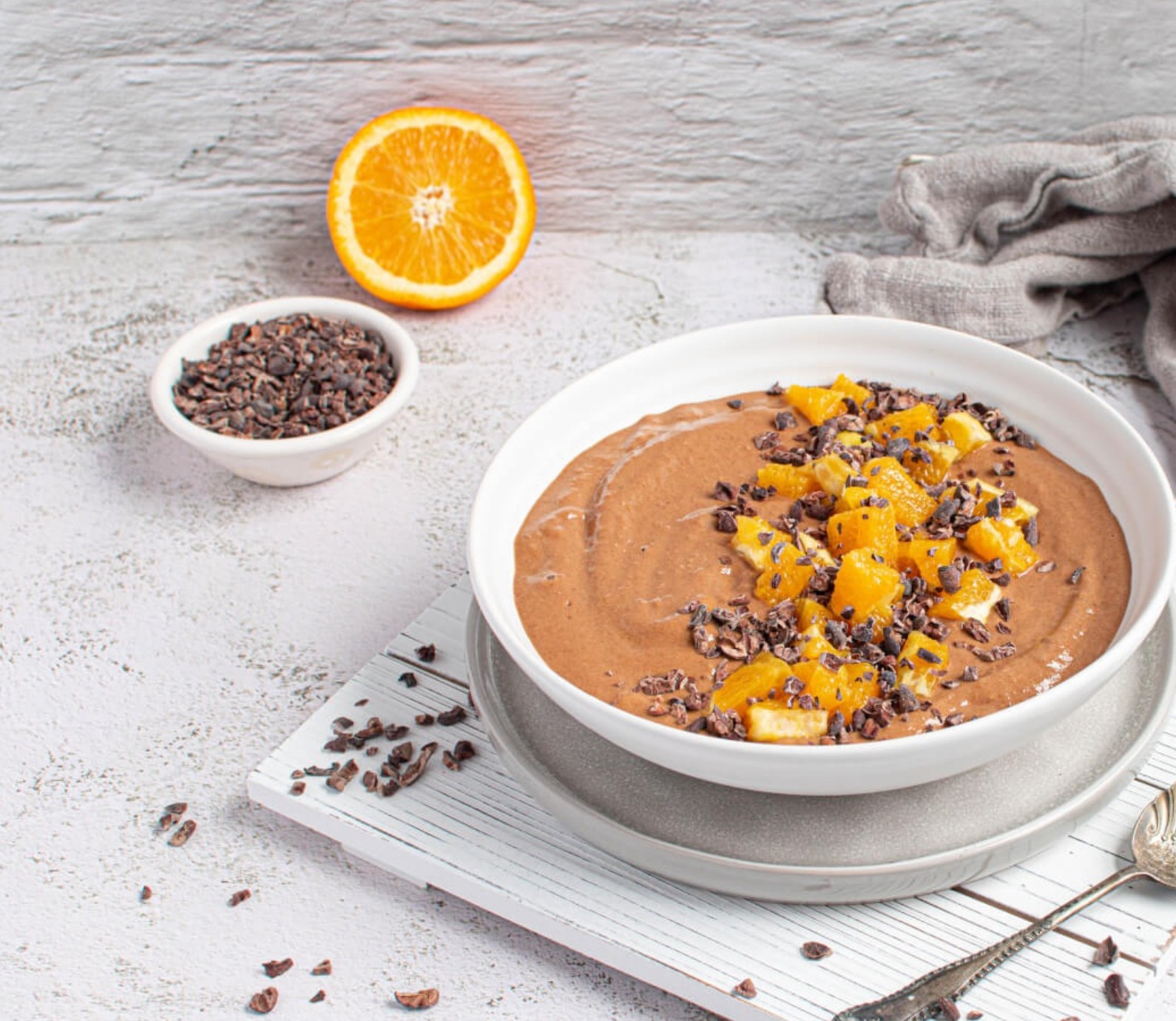 Thick smoothie bowl made with chocolate, orange, and ginger, topped with coconut and seeds—a nutrient-dense, hormone-friendly treat.