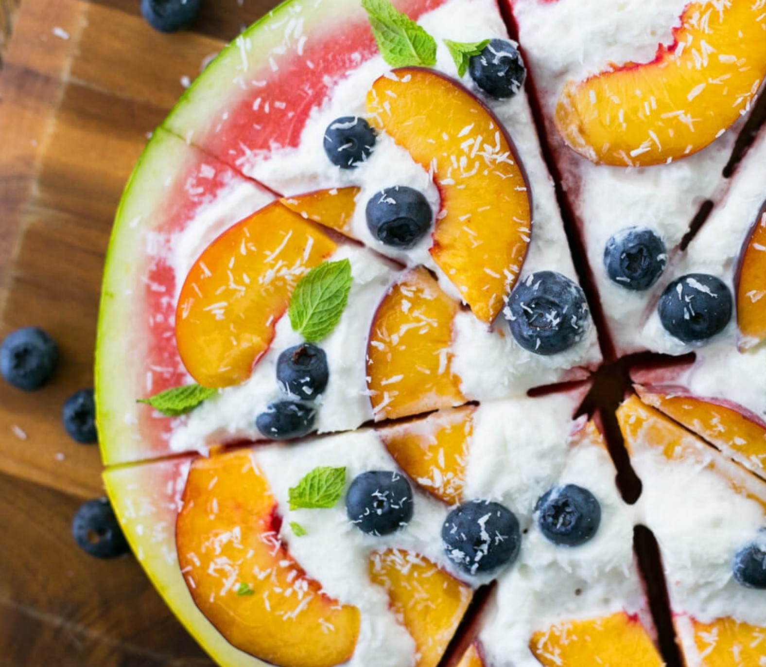 Sliced watermelon pizza topped with coconut yogurt, berries, and mint—an AIP-friendly, refreshing summer treat.