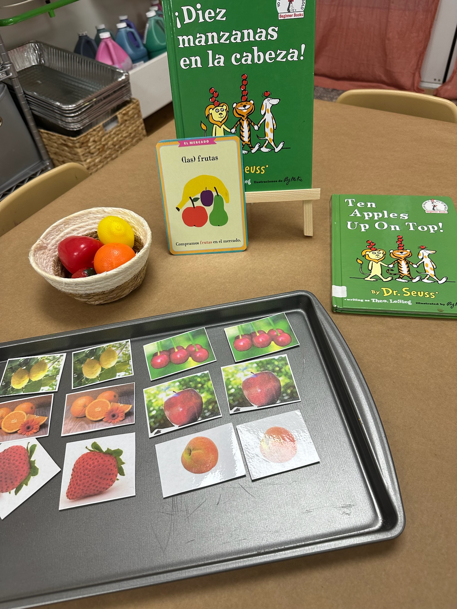 Preschool literacy and sorting activity featuring fruit cards, bilingual books, and hands-on learning materials.