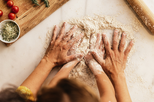 Parent and child hands in flour on a kitchen counter